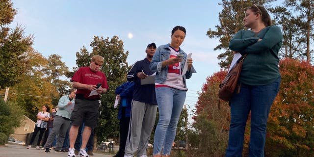 Voters fill out forms as they wait in line to cast ballots in the last hour of early voting in the Atlanta suburb of Tucker, Ga., on Friday, Nov. 4, 2022.