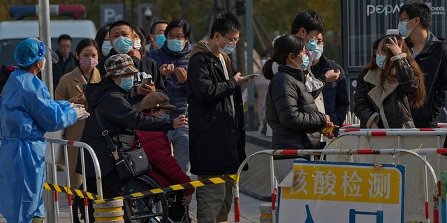 People use their smartphones to scan health check QR codes before receiving their regular COVID-19 throat swabs at a coronavirus testing site in Beijing on Tuesday, November 8, 2022.