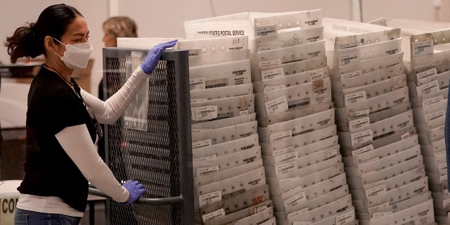 An election worker arrives with ballots to be tabulated inside the Maricopa County Recorders Office, Wednesday, Nov. 9, 2022, in Phoenix. 