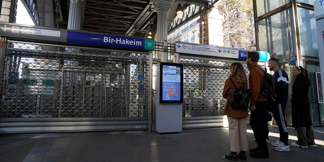 People stand in front of a closed metro station on Thursday, November 10, 2022 in Paris. 