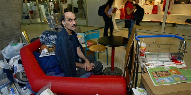 FILE - Merhan Karimi Nasseri sits among her belongings in Terminal 1 of Roissy Charles De Gaulle Airport, north of Paris, on August 11, 2004. 