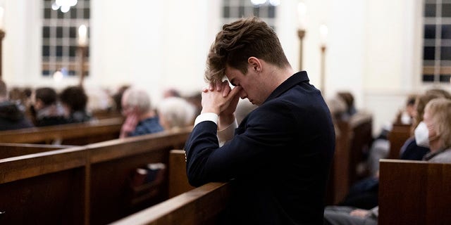 A person prays at a service at St. Paul's Memorial Church in response to the shootings that happened on the University of Virginia campus the night before in Charlottesville, Va., Monday, Nov. 14, 2022. 