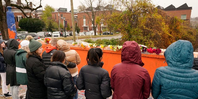 Mourners look over flowers that line a bridge near the scene of a shooting on the grounds of the University of Virginia Tuesday Nov. 15, 2022, in Charlottesville. Authorities say three people have been killed and two others were wounded in a shooting at the University of Virginia and a student suspect is in custody. 