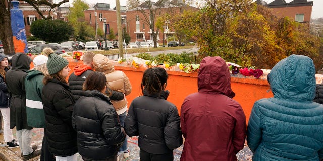 Mourners look over flowers that line a bridge near the scene of a shooting on the grounds of the University of Virginia Tuesday Nov. 15, 2022, in Charlottesville. Authorities say three people have been killed and two others were wounded in a shooting at the University of Virginia and a student suspect is in custody.