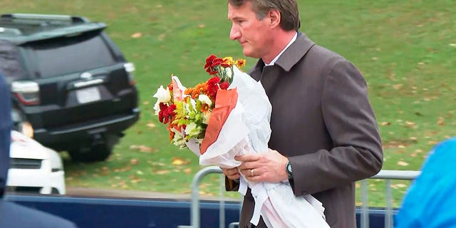 Virginia Gov. Glenn Youngkin brings flowers to a memorial service at the University of Virginia, Tuesday, Nov. 15, 2022, in Charlottesville. 