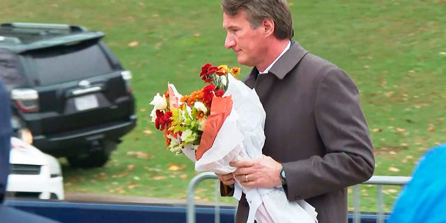 Virginia Gov. Glenn Youngkin brings flowers to a memorial service at the University of Virginia, Tuesday, Nov. 15, 2022, in Charlottesville.