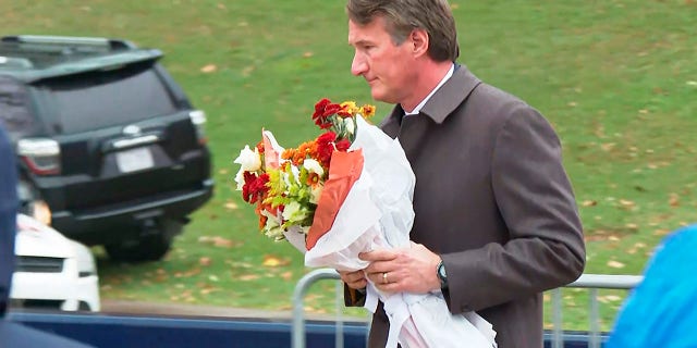 Virginia Gov. Glenn Youngkin brings flowers to a memorial service at the University of Virginia, Tuesday, Nov. 15, 2022, in Charlottesville. 