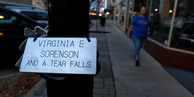 A plaque honoring Virginia "Ginny" Sorenson rests on a lamp post on Nov. 3, 2022, along Main Street in Waukesha, Wis., as Donna Kalik walks nearby.