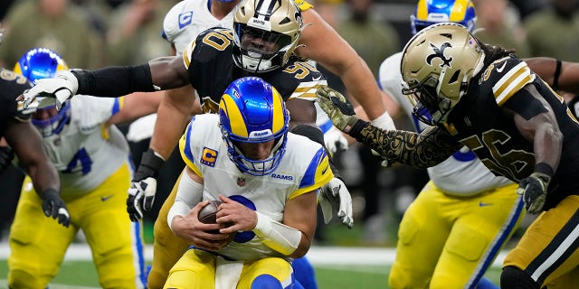 Los Angeles Rams quarterback Matthew Stafford is sacked by New Orleans Saints defenders Tanoh Kpassagnon (90) and Demario Davis (56) in the second half of an NFL football game in New Orleans, Sunday, Nov. 20, 2022.