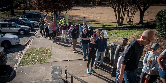 Voters wait in a growing line to cast their ballots at the Bessie Branham Park polling location on Sunday, Nov. 27, 2022, in Atlanta.