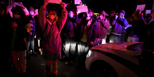 Protesters hold up blank papers and chant slogans as they march in Beijing, Sunday, Nov. 27, 2022. 