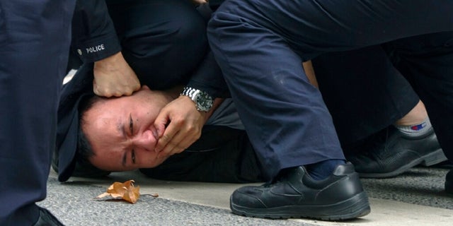 In this photo taken on Sunday, policemen pin down and arrest a protester during a protest on a street in Shanghai.