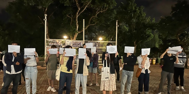 Protesters hold up blank white papers during a commemoration for victims of a recent Urumqi deadly fire in Central in Hong Kong, Monday, Nov. 28, 2022. 