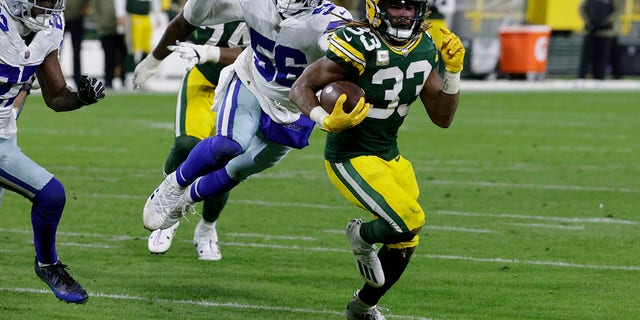 Green Bay Packers running back Aaron Jones (33) sprints past Dallas Cowboys defensive end Dante Fowler Jr. (56) as he heads to the end zone to score a touchdown during the first half, Nov. 13, 2022, in Green Bay, Wisconsin.