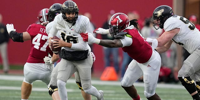 Purdue quarterback Aidan O'Connell, #16, runs from Indiana's James Head Jr., second from right, during the first half of an NCAA college football game, Saturday, Nov. 26, 2022, in Bloomington, Indiana.