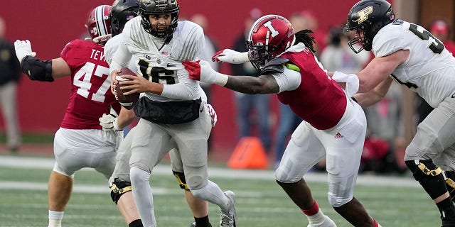 Purdue quarterback Aidan O'Connell, #16, runs from Indiana's James Head Jr., second from right, during the first half of an NCAA college football game, Saturday, Nov. 26, 2022, in Bloomington, Indiana.