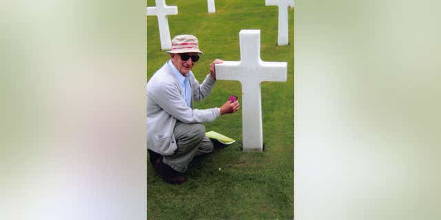 Andy Andrews pays his respects to a slain soldier at the Normandy American Cemetery in Normandy, France.