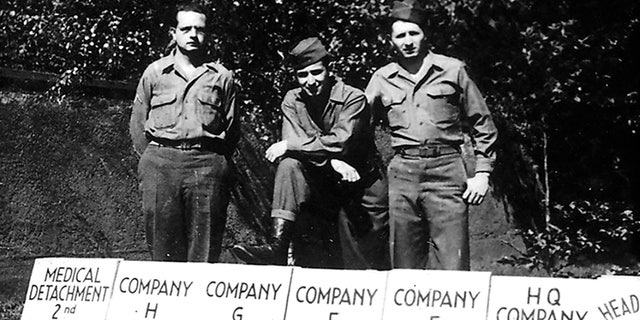 Andy Andrews, au centre, avec d'autres soldats derrière les panneaux indiquant le QG du IIe Bataillon.