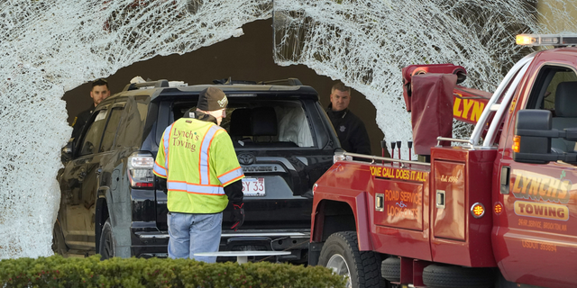 Workers use a tow truck to remove a damaged SUV from inside an Apple store on Nov. 21, in Hingham, Massachusetts. At least one person was killed and multiple others were injured Monday when the SUV crashed into the store, authorities said.