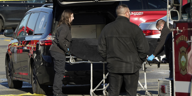 Officials transfer a body into a medical examiner's vehicle outside an Apple store in Hingham, Massachusetts, on Nov. 21.