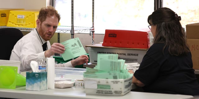 Maricopa County recorder Stephen Richer, left, opens mail-in ballots at the Maricopa County Tabulation and Election Center on Nov. 11, 2022, in Phoenix. 