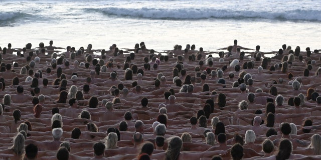 Attendees pose nude during sunrise on Sydney's Bondi Beach for US fine art photographer Spencer Tunick to raise awareness of skin cancer, 26 November 2022.