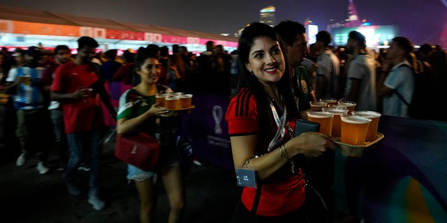 Fans carry their beers at a fan zone ahead of the FIFA World Cup, in Doha, Qatar, Saturday, Nov. 19, 2022.