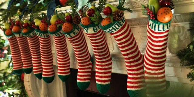 FILE: Traditional stockings of the Biden family hang from the fireplace in the State Dining Room of the White House during a press preview of holiday decorations on November 28, 2022 in Washington, DC.