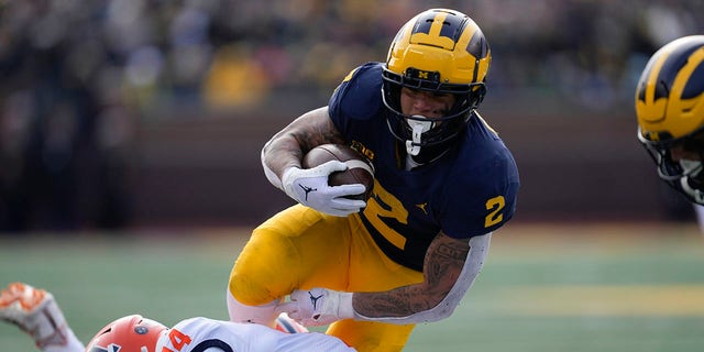 Michigan running back Blake Corum (2) runs the ball as Illinois defensive back Xavier Scott (14) defends in the first half of a game in Ann Arbor, Mich., Saturday, Nov. 19, 2022.