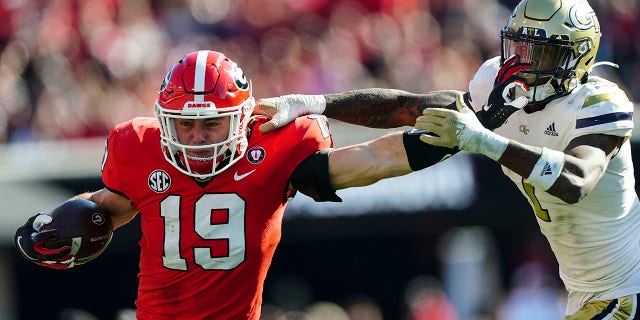 Georgia tight end Brock Bowers (19) fends off Georgia Tech defensive back Zamari Walton (7) as he runs after a catch during the first half of an NCAA college football game Saturday, 26 November 2022 in Athens, Georgia.  Bowers was called for a face masking penalty.