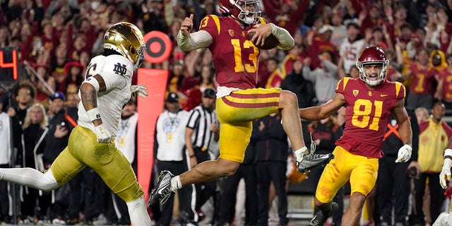 Southern California quarterback Caleb Williams jumps in for a touchdown as Notre Dame safety Xavier Watts, left, defends and Southern California wide receiver Kyle Ford watches during the second half of an NCAA college football game Saturday, Nov. 26, 2022, in Los Angeles. 