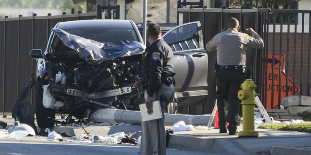 Two investigators stand next to a mangled SUV that struck Los Angeles County sheriff's recruits in Whittier, California, on Wednesday.