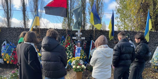 Several gather around in a cemetery in Kyiv. 