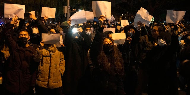 Los manifestantes sostienen papeles en blanco y corean consignas mientras marchan en Beijing, el domingo 27 de noviembre de 2022. Los manifestantes enojados por las duras medidas contra el virus han pedido al poderoso líder de China que renuncie, una reprimenda sin precedentes como autoridades en al menos ocho ciudades. luchaban por sofocar las protestas del domingo que representan un raro desafío directo al gobernante Partido Comunista.