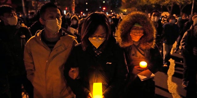 Los manifestantes sostienen velas mientras marchan en Beijing, el domingo 27 de noviembre de 2022. Los manifestantes enojados por las estrictas medidas contra el virus han pedido al poderoso líder de China que renuncie, una reprimenda sin precedentes mientras las autoridades en al menos ocho ciudades luchaban por sofocar las protestas del domingo que representan un raro desafío directo al gobernante Partido Comunista.