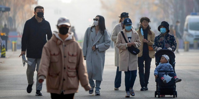 People wearing face masks walk along a pedestrian shopping street in Beijing's Wangfujing shopping district on Saturday, Nov. 19, 2022.