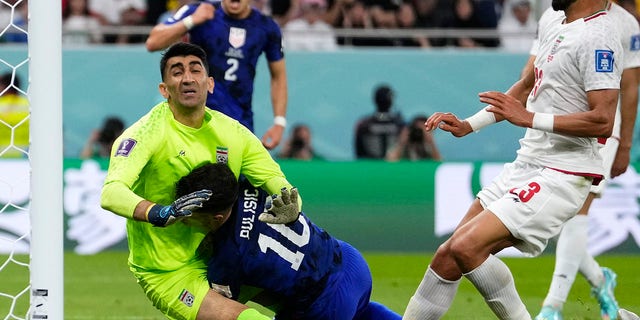 Christian Pulisic of the United States, center, collides with Iranian goalkeeper Alireza Beiranvand, left, after scoring the United States' first goal during the World Cup Group B soccer match between Iran and the United States at Al Stadium Thumama in Doha, Qatar, on Tuesday.  November 29, 2022. 