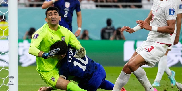 Christian Pulisic de los Estados Unidos, centro, choca con el portero iraní Alireza Beiranvand, izquierda, después de marcar el primer gol de los Estados Unidos en el partido de fútbol del Grupo B de la Copa Mundial entre Irán y los Estados Unidos en el Estadio Al Thumama en Doha, Qatar. martes, 29 de noviembre de 2022. 