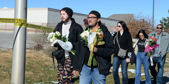 Tim Bates, Erric Ramirez, Malissa Ramirez, Trinity Ramirez and Fred Ramirez deliver flowers near a gay nightclub in Colorado Springs, Colo., Nov. 20, where a shooting occurred.