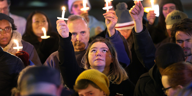 People hold a vigil at a makeshift memorial near the Club Q nightclub on Nov. 20, 2022, in Colorado Springs, Colorado.