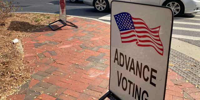 A sign showing the way for voters stands outside a Cobb County voting building during the first day of early voting, Monday, Oct. 17, 2022, in Marietta, Ga.