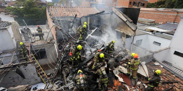 Firefighters work at the crash site of a small plane that crashed into homes in a residential area of ​​Medellin, Colombia, on November 21, 2022.