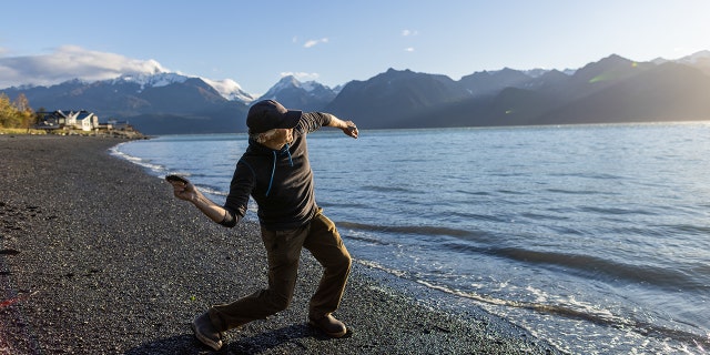 A man jumps rocks during a walk on the beach at Lowell Point in Seward, Alaska.