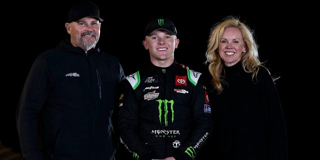 تای گیبس، راننده تویوتای هیولا انرژی شماره 54، پس از برنده شدن در مسابقات قهرمانی سری Xfinity NASCAR در فینیکس ریس وی در 5 نوامبر 2022 در آوندیل، آریزونا، با پدرش، کوی گیبز و مادرش، هدر گیبز، عکس می گیرد.