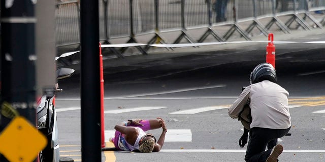 Brazil's Daniel Do Nascimento, left, lies on the pavement after collapsing during the New York City Marathon, Nov. 6, 2022, in New York.