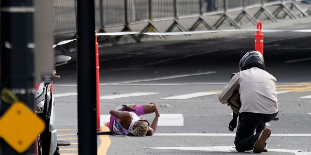 Brazil's Daniel Do Nascimento, left, lies on the pavement after collapsing during the New York City Marathon, Nov. 6, 2022, in New York.