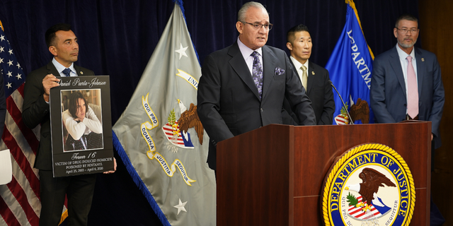 United States Attorney Martin Estrada, left, holds a picture of the late Daniel Puerta-Johnson, 16, a victim of Fentanyl poisoning, as his father, Jaime Puerta, president of Victims of Illicit Drugs, at the podium, joins the U.S. Attorney's Office Central District of California office to address the widespread damage caused by fentanyl in Los Angeles, on Monday, Nov. 21.