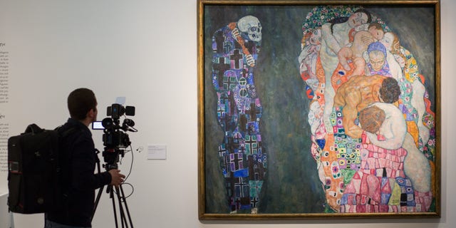 A man films "Death and Life," a painting by Gustav Klimt, at Leopold Museum in Vienna, Jan. 28, 2016.