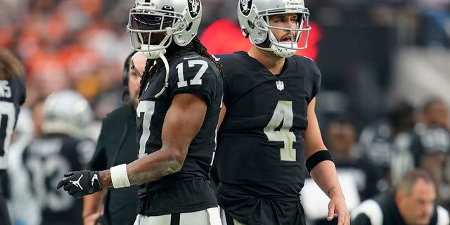 Las Vegas Raiders wide receiver Davante Adams, #17, left, and quarterback Derek Carr, #4, right, watch from the sidelines during the second half of an NFL football game against the Denver Broncos, Sunday, Oct. 2, 2022, in Las Vegas.