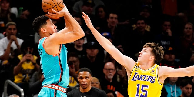 Phoenix Suns' Devin Booker shoots a three pointer against Los Angeles Lakers' Austin Reaves (15) during the first half of an NBA basketball game in Phoenix, Tuesday, Nov. 22, 2022.